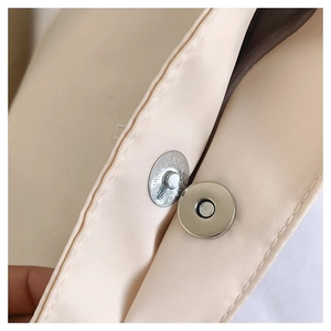 Detail of silver magnetic clasp on nylon tote bag with smooth satin lining