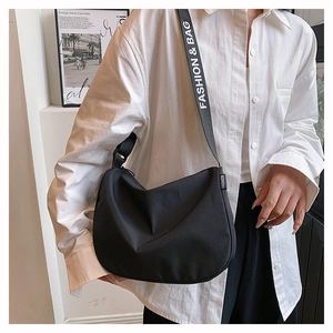 Close-up of black canvas crossbody bag featuring adjustable wide fashion letter strap