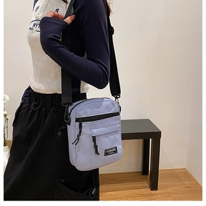Detail of light purple nylon crossbody bag with multi-pocket design and adjustable strap