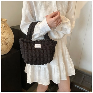 Détail du sac à main noir gaufré montrant le tissu bouffant et l'étiquette tissée