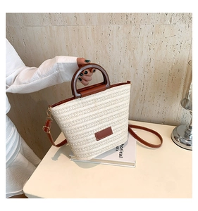 Détail du sac cabas en paille tissée avec poignées en bois rondes et sangle en cuir
