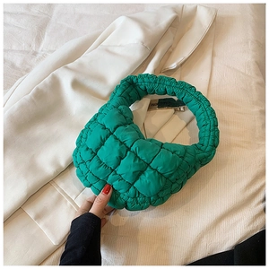Detail of lime green quilted handbag featuring a branded metal clip and ruched handle