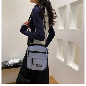 Detail view of the vertical canvas crossbody bag with multiple zipper compartments