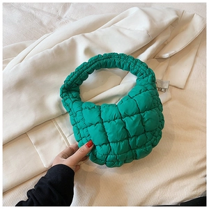 Detailed close-up of neon green quilted puffer handbag with soft pleat handle texture