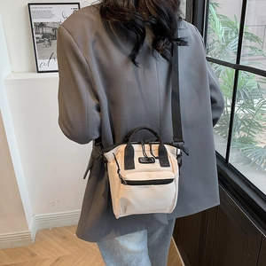 Mini beige Oxford cloth crossbody bag with black handles and strap worn by model
