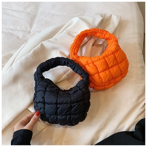 Detail shot of quilted puffer cloud bags in black and orange showing soft texture