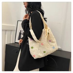 Close-up of beige plush tote bag with colorful floral embroidery and fringe texture