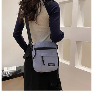 Vertical lavender nylon crossbody bag worn by model against a minimalist studio wall