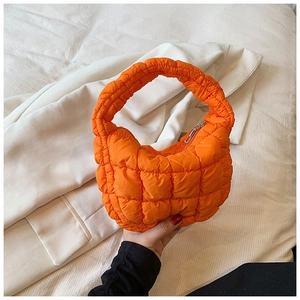 Close-up of orange puffer cloud bag with quilted texture and metal zipper detail