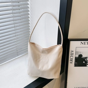 Minimalist beige nylon tote bag with embroidery on a windowsill with soft window shadows