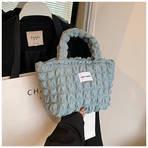Gros plan du tissu gaufré bleu clair et de l'étiquette Love Fashion sur le sac à main