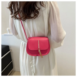 Detailed back view of a rose red crossbody bag with tassel on a white dress model
