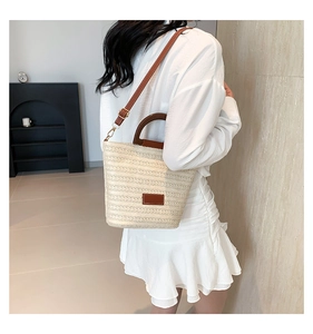 Détail du sac seau tissé beige avec bandoulière en cuir marron et poignée en bois