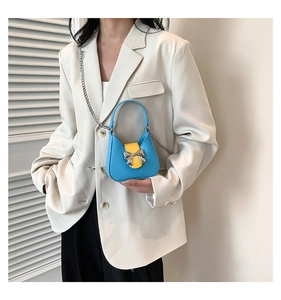Detail showing high contrast blue and yellow mini saddle bag with silver bow clasp
