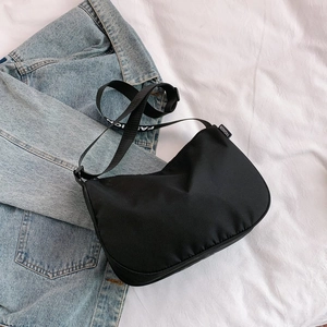Close-up of black canvas crossbody bag with Fashion logo strap on denim jacket