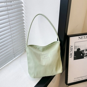 Minimalist light green nylon tote bag with embroidery displayed in a natural light setting