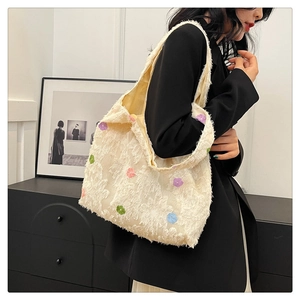 Detail of cream tote bag featuring textured fringe floral fabric and colorful embroidery