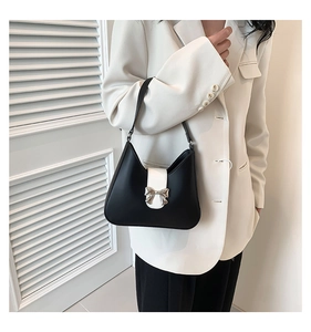 Detailed view of black and white contrast shoulder bag with silver bow ornament