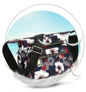 Detail view of floral nylon crossbody bag with multi-zipper pockets and wide strap