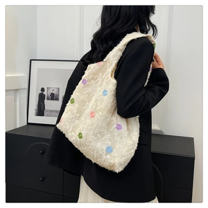Detail of cream tote bag featuring colorful flower embroidery and textured fringe fabric