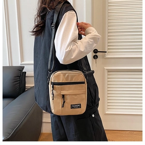 Khaki crossbody bag featuring a front zipper pocket and adjustable black nylon strap