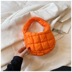 Close-up of bright orange quilted bubble handbag texture with stylish puffy stitching