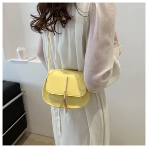 Fashionable yellow square crossbody bag for women with golden metal tassel detail on dress