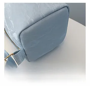 Detail showing light blue pleated fabric texture, precise stitching and gold metal hardware