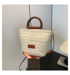 Détail du sac seau tissé crème avec poignées rondes marron et bandoulière amovible