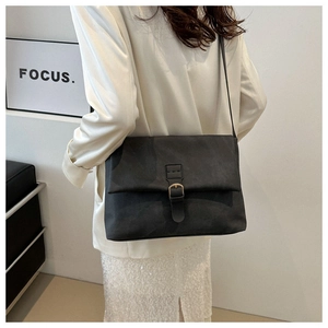 Détail d'un sac à bandoulière gris foncé mat avec boucle porté par un mannequin