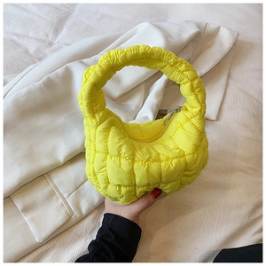 Detail of a yellow quilted cloud handbag with soft puffed texture and metallic top zipper
