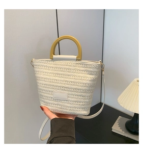 Détail du sac seau tissé blanc avec poignée en résine jaune et finitions en cuir