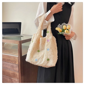 Detail of cream bouclé tote bag with colorful flower patterns in a lifestyle setting