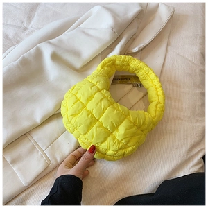 Detailed texture of bright yellow quilted nylon material on cloud handbag
