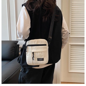 Detailed back-side view of a white tactical nylon crossbody bag with black wide straps