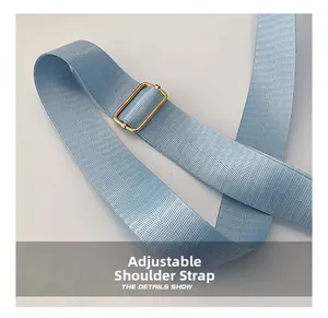 Detailed close-up of light blue adjustable woven shoulder strap with gold metal buckle