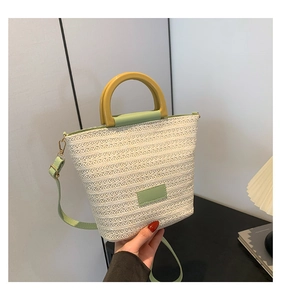 Détail du sac tissé crème avec bordure verte et poignée ronde jaune élégante