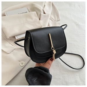 Detail of elegant black crossbody bag featuring a designer gold tassel metal lock buckle