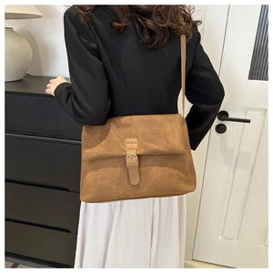 Sac bandoulière en daim marron givré avec boucle de ceinture porté par un mannequin