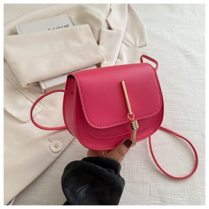 Detail view of fuchsia saddle bag with gold metal hardware and elegant tassel pendant