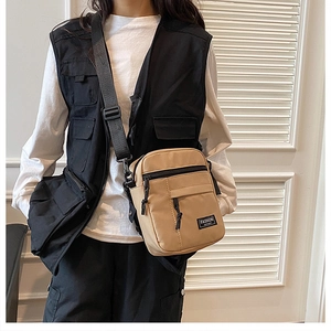 Close-up of tan canvas crossbody phone bag on model showing tactical streetwear details