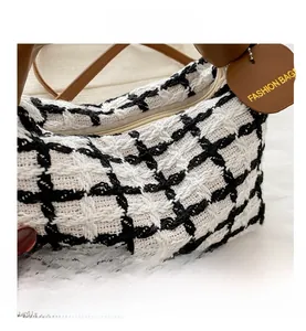 Close-up of black and white checkered tweed texture and brown leather heart tag