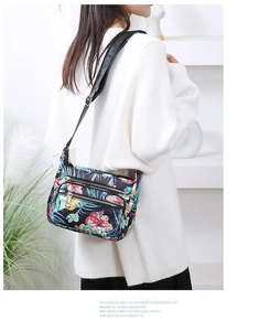 Detail view of floral print nylon shoulder bag showing dual metal zippers and strap