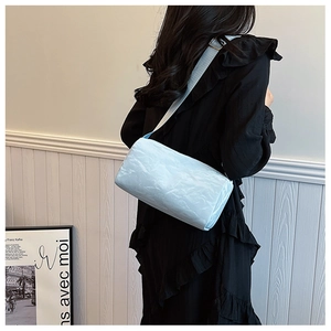 Detailed view of light blue cylindrical shoulder bag with unique crinkled texture fabric