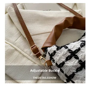 Close-up of adjustable brown leather strap and golden metal buckle on plaid handbag