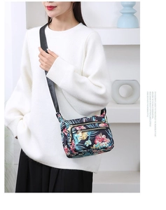 Detail view of floral nylon crossbody bag with wide strap and multiple zipper pockets