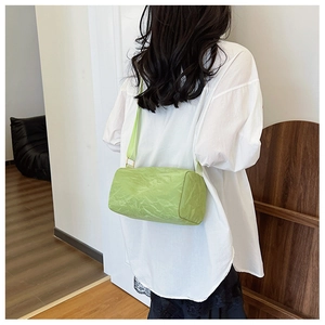 Detail of green cylinder bag with crinkled nylon texture and gold metal hardware