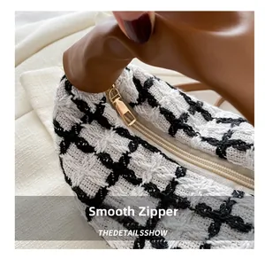 Macro detail of smooth golden metal zipper on black and white plaid tweed bag