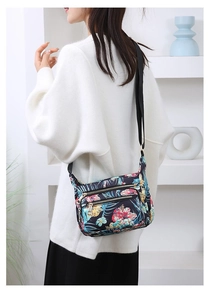 Model wearing a lightweight floral nylon crossbody bag with multiple zip pockets