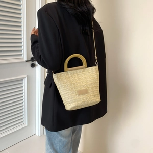 Sac seau chic en paille tressée pour femme avec bandoulière en cuir dans un décor épuré